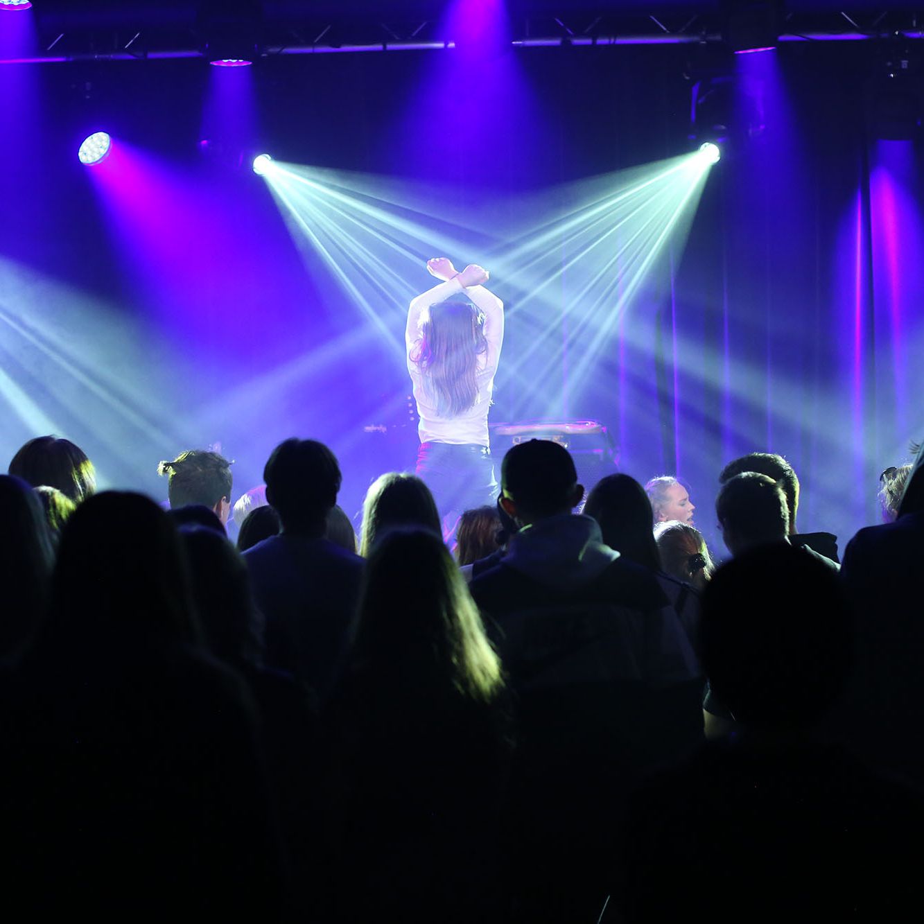 Jente står med ryggen til på scene